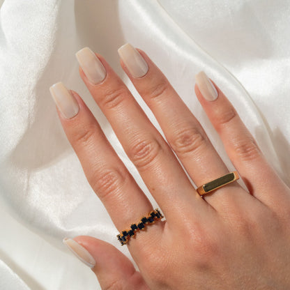 Hand wearing two rings on a white fabric background