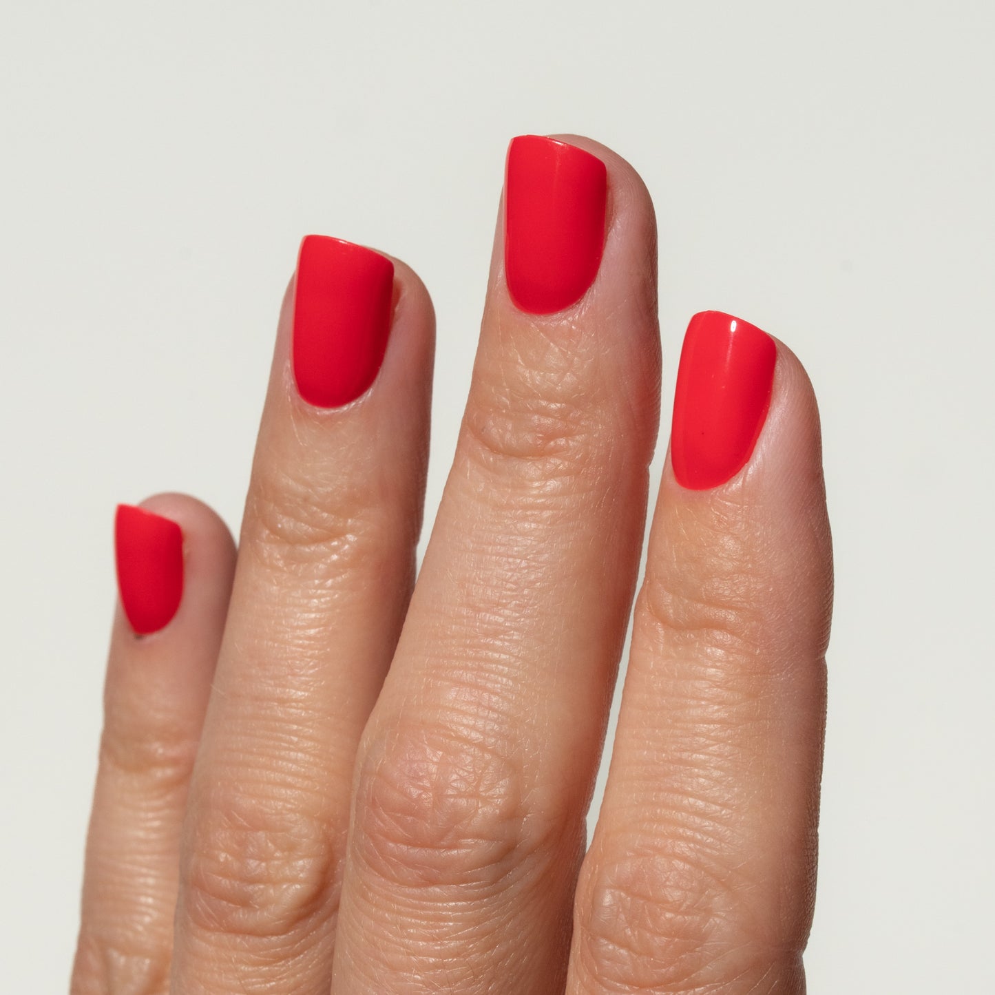 Hand with red press on nails on a plain background