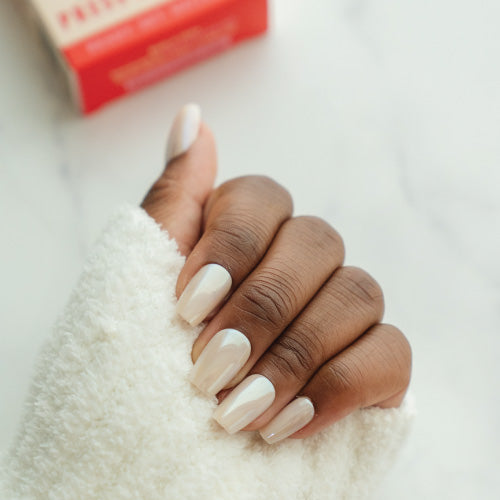 Hand with cream press on nails on a soft white surface