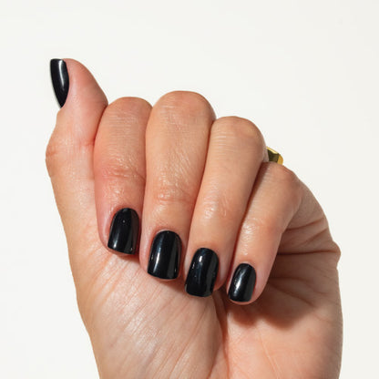 Hand with black press on nails on a plain background
