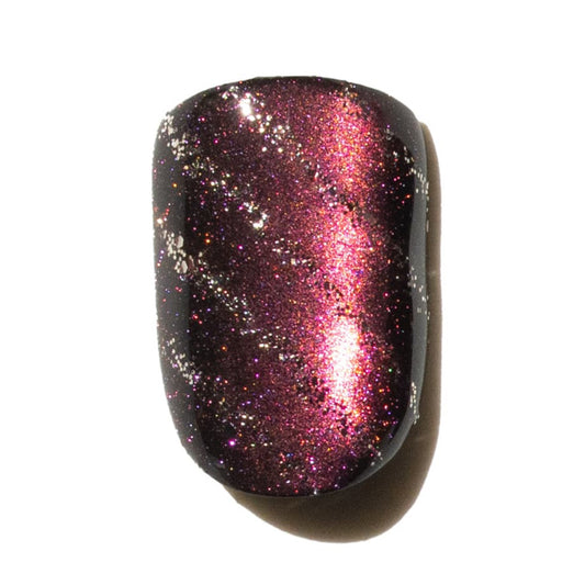 Press on nail with a glittery purple and gold striped design on a white background