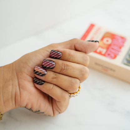 Hand with patterned nails holding a small box on a light background