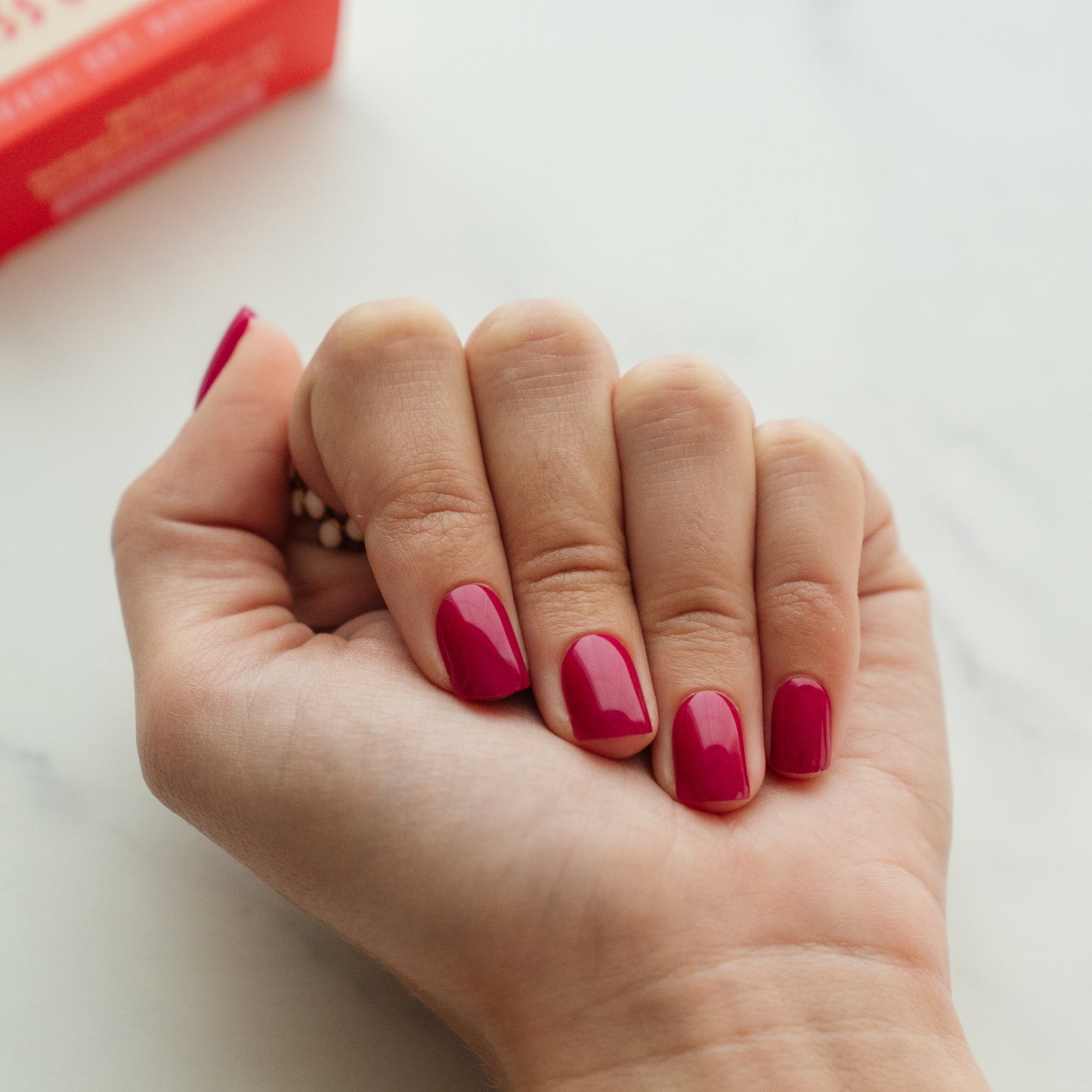 Hand with berry pink press on nails on a light background