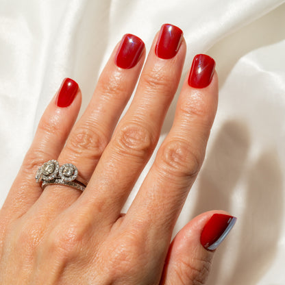 Hand with red press on nails wearing a silver ring on a white background