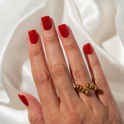 Hand with red press on nails wearing a gold ring on a white background