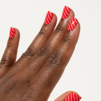 Hand with red and pink striped press on nails on a white background
