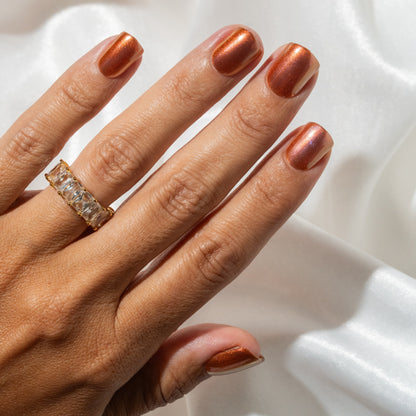 Hand with metallic press on nails and a ring on a white background