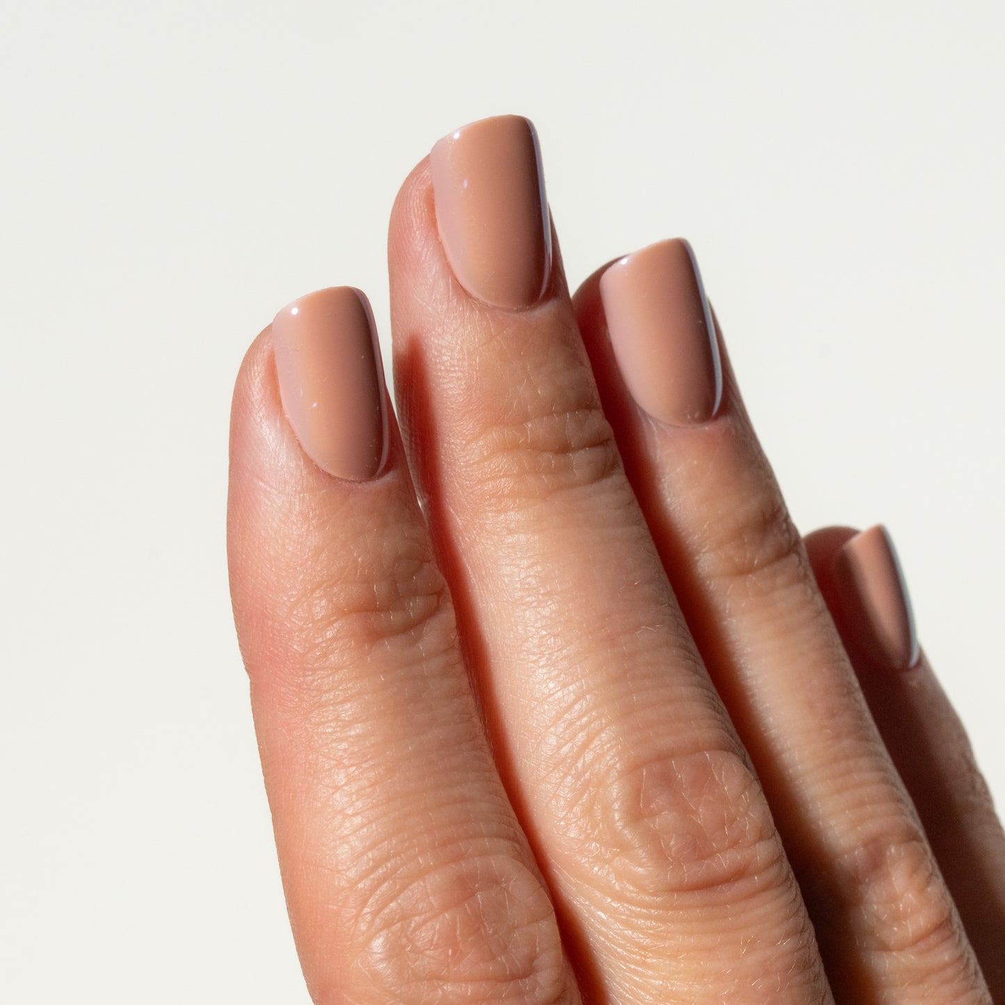 Close-up of a hand with rose pink press on nails on a light background