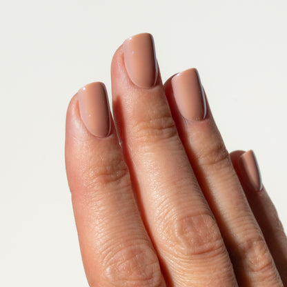 Close-up of a hand with rose pink press on nails on a light background