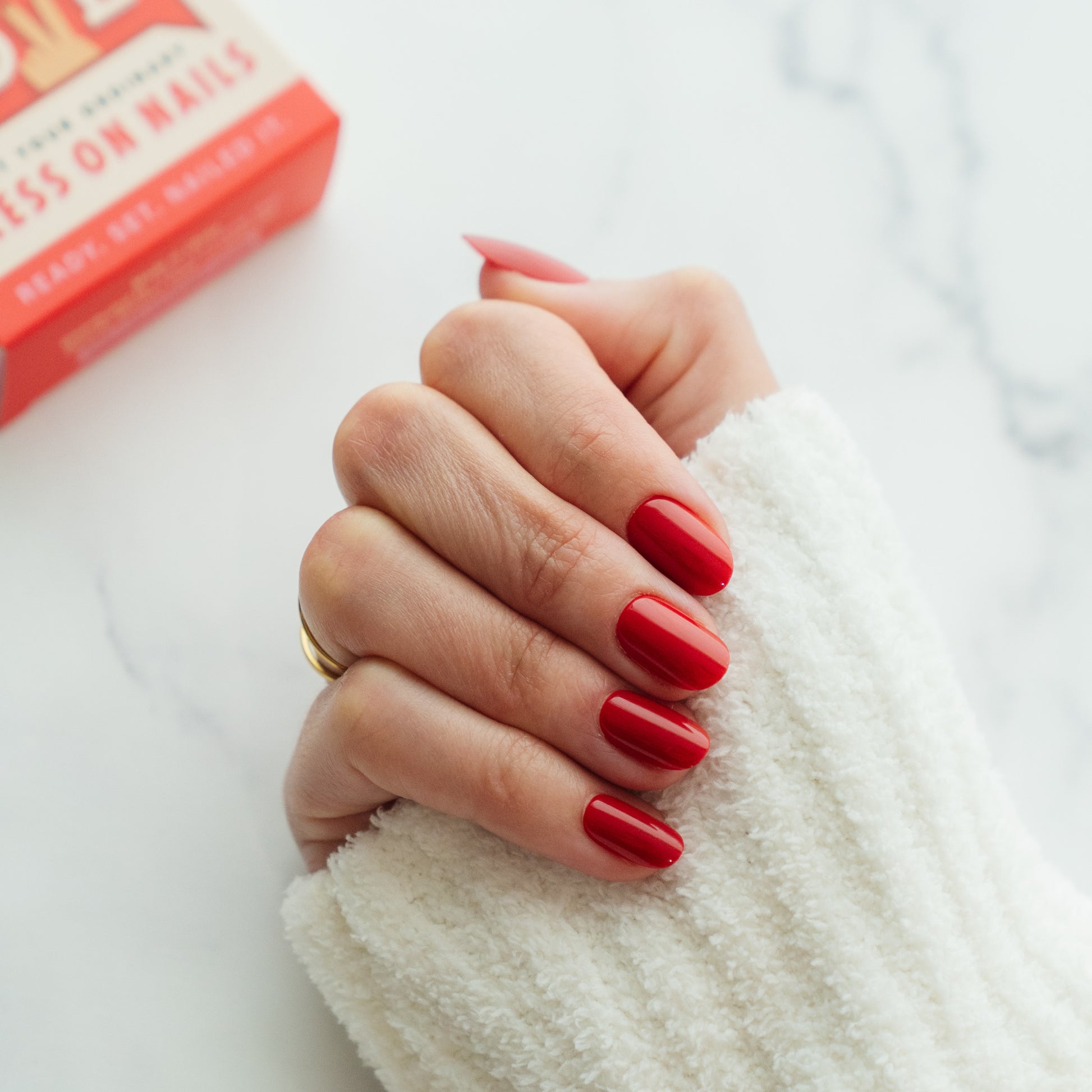 Hand with red press on nails in a medium length on a white background