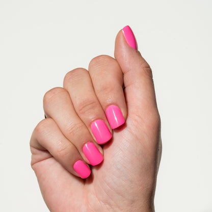 Hand with neon pink press on nails on a light gray background