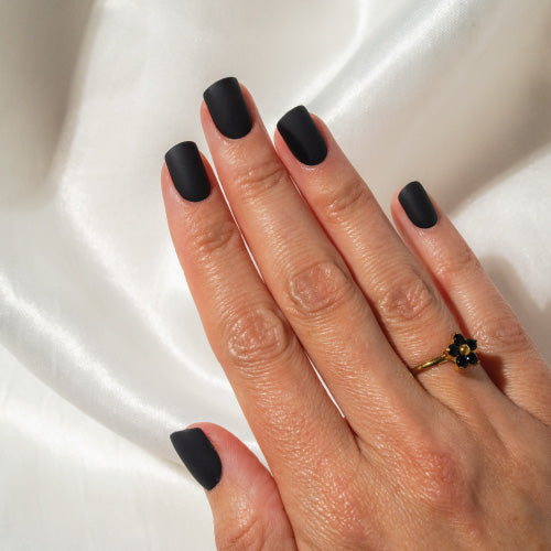 Hand with black press on nails on a white fabric background
