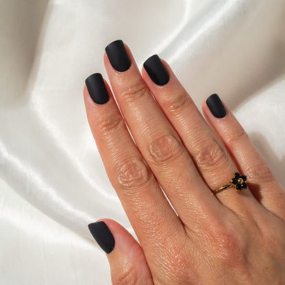 Hand with black press on nails on a white fabric background