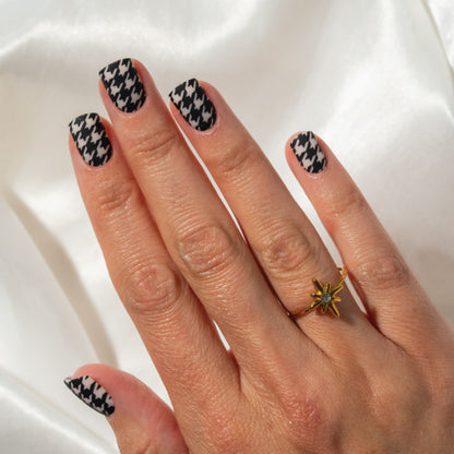 Hand with houndstooth patterned press on nails on a white background