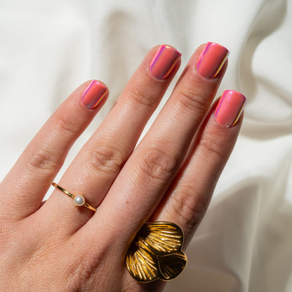 Hand with pink press on nails and gold rings on a white background