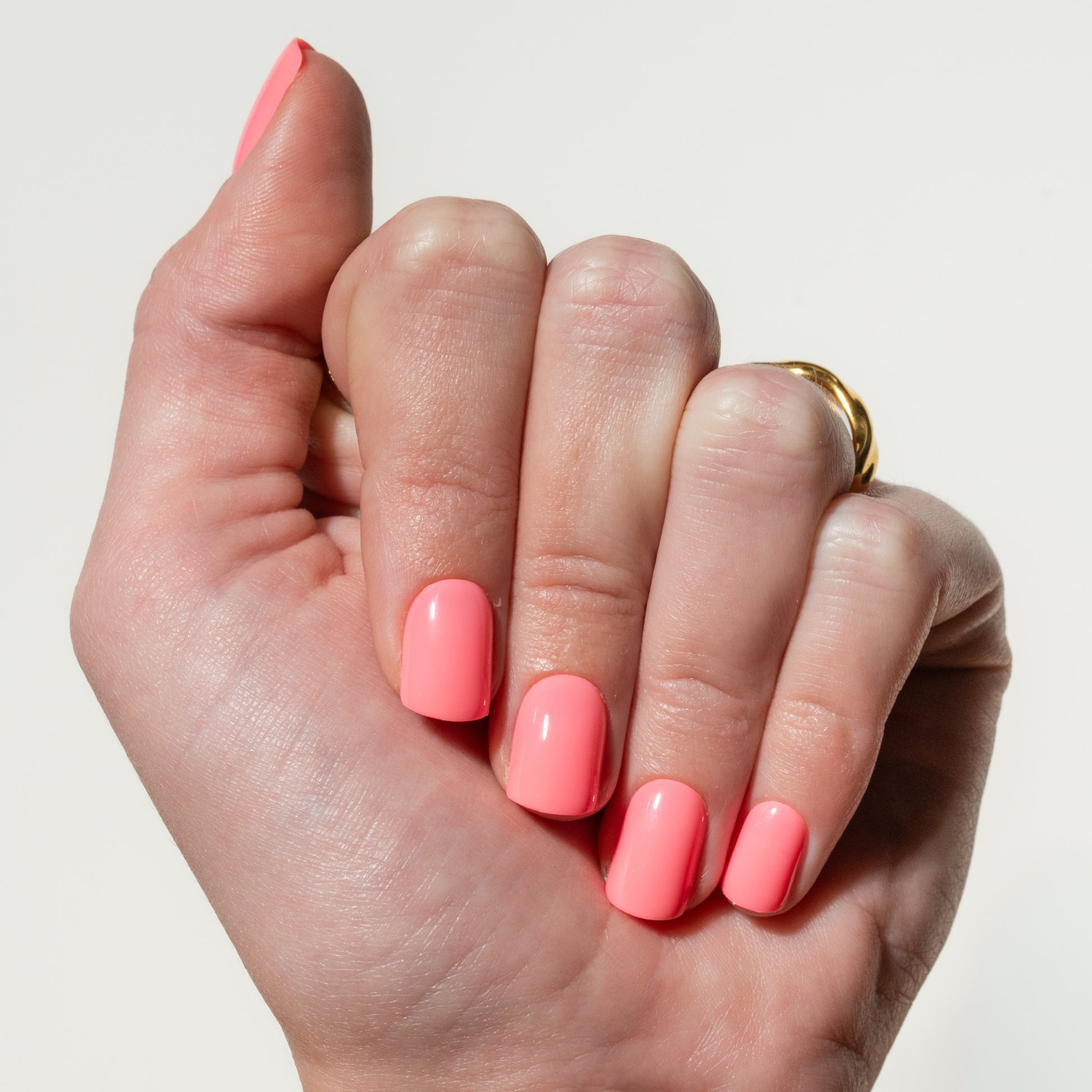 Hand with pink press on nails on a plain background