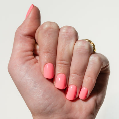 Hand with pink press on nails on a plain background