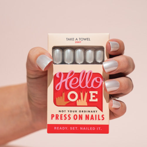 Box of press-on nails with 'Hello Love' branding held by a hand with white press on nails.