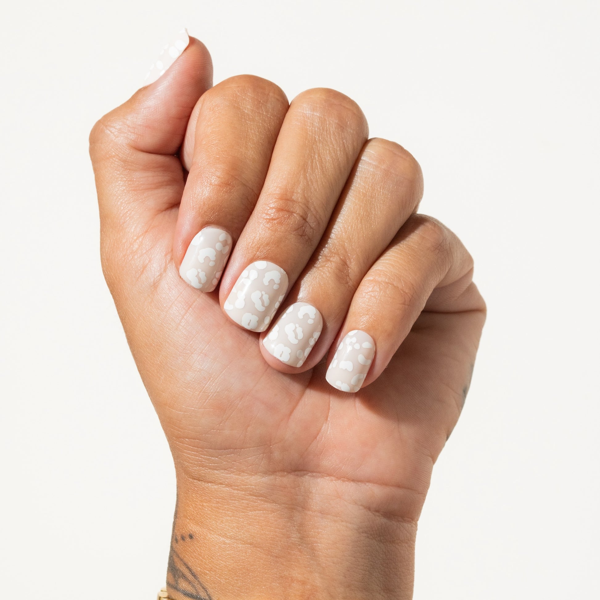 Hand with white leopard press on nails on a light background