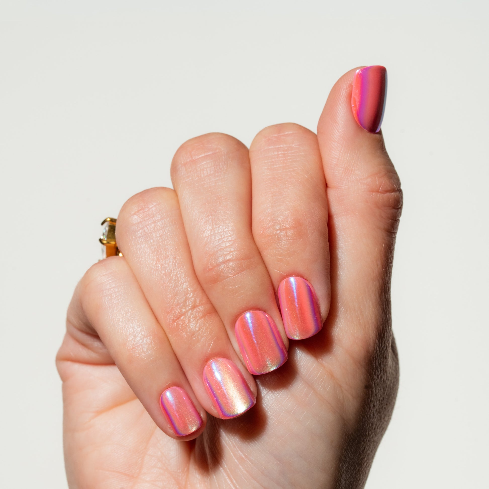 Hand with pink and purple gradient press on nails on a light background